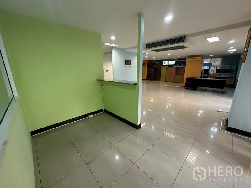 Office Space for sale - Entry alcove beside the open-plan space with green accent wall and sheer curtains.