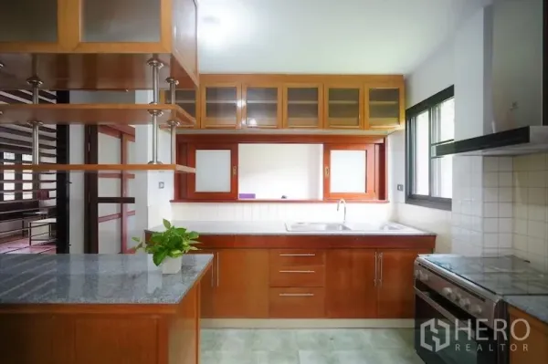 Detached House for rent in Chatuchak, Bangkok - Bright closed kitchen with wood cabinetry, granite countertop, double sink, and a large window.