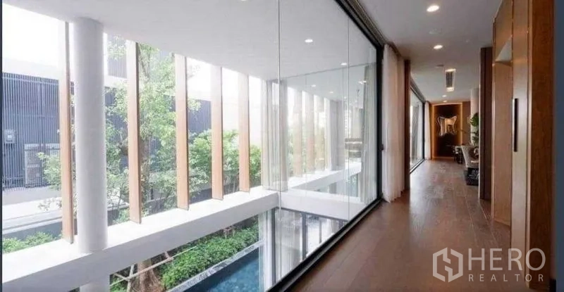 独立式住宅 出售在Huai Khwang, Bangkok - 二层走廊整面玻璃，可俯瞰庭院泳池与绿树。