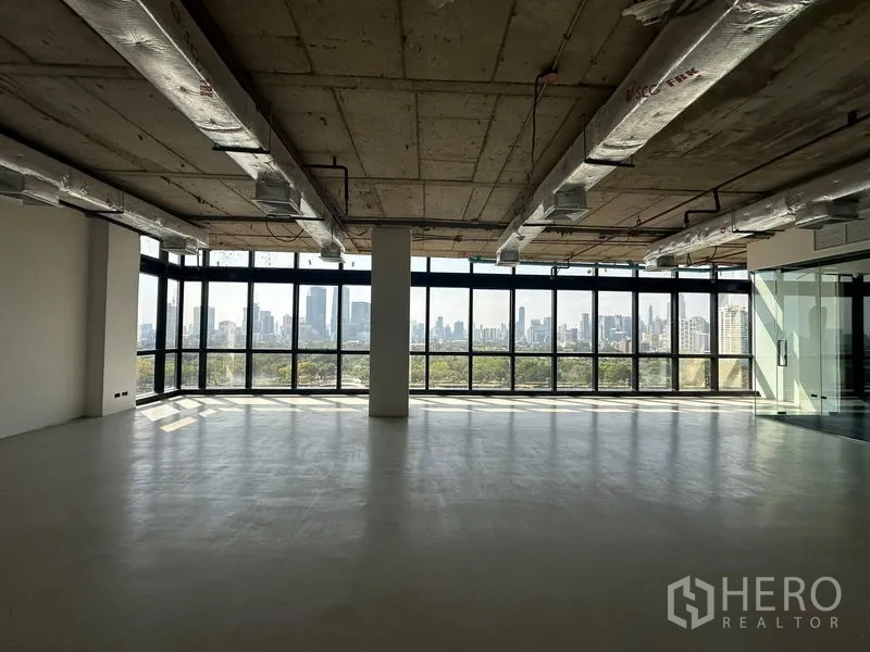 办公空间 出租在Watthana, Bangkok - 宽敞毛坯办公区，裸露风管天花、中央立柱与环幕窗，远眺城市天际线。