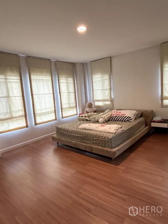 Detached House for sale in Bang Kapi, Bangkok - Master bedroom with wraparound windows and warm wood floors.