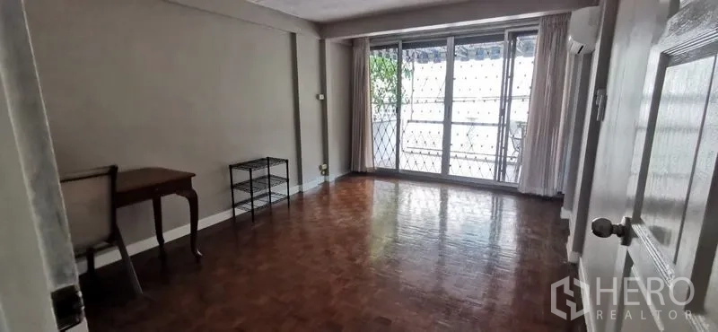 联排别墅 出租在Watthana, Bangkok - 宽敞客厅，拼花木地板，推拉门通向带防盗栏的阳台