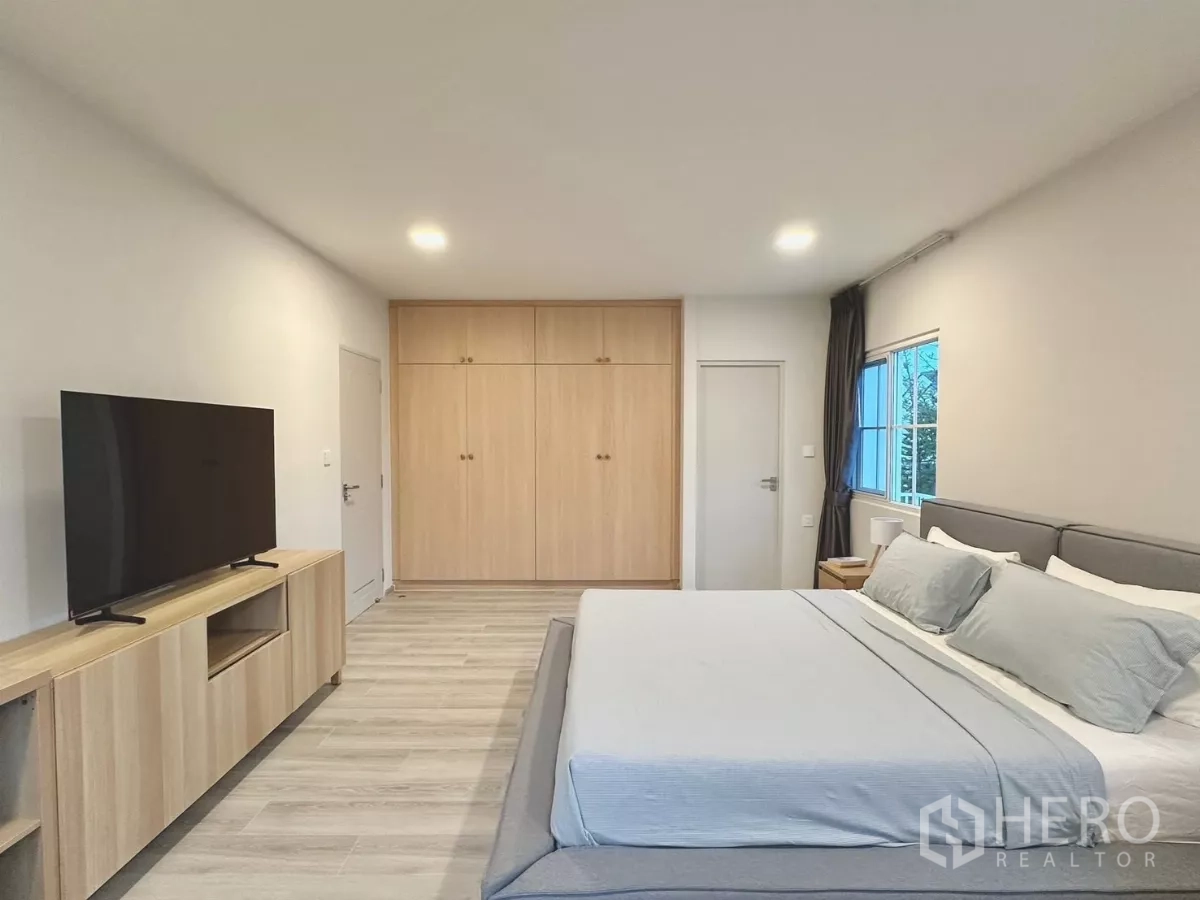 Detached House for rent in Bang Phli, Samut Prakan - Master bedroom media wall with large TV and study desk by the window.