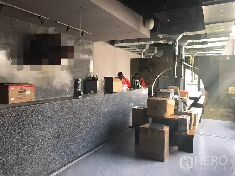 พื้นที่ขายปลีก ให้เช่าในWatthana, Bangkok - ภายในสไตล์ลอฟต์ของพื้นที่ค้าปลีก เคาน์เตอร์หินยาว ท่อดักท์โครงสร้าง และมีกล่องวางบนโต๊ะ