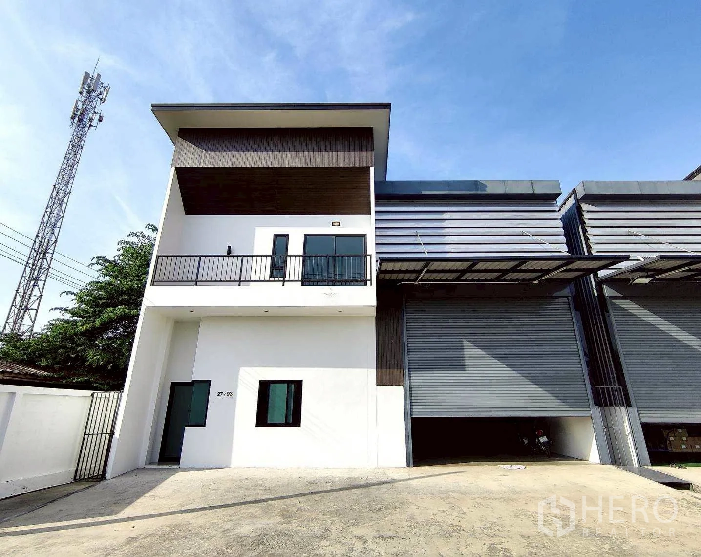 Warehouse for rent in Lam Luk Ka, Pathum Thani - Left-side unit showing balcony office above a large shuttered loading bay.