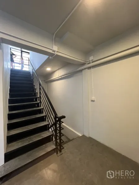 Retail Space for rent in Watthana, Bangkok - Stair corridor with black metal handrail, white walls and gray tiled floor.