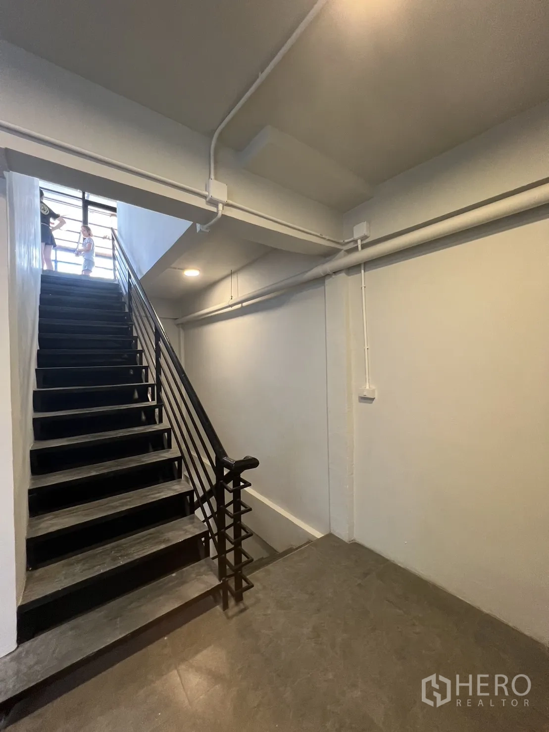 Retail Space for rent in Watthana, Bangkok - Stair corridor with black metal handrail, white walls and gray tiled floor.