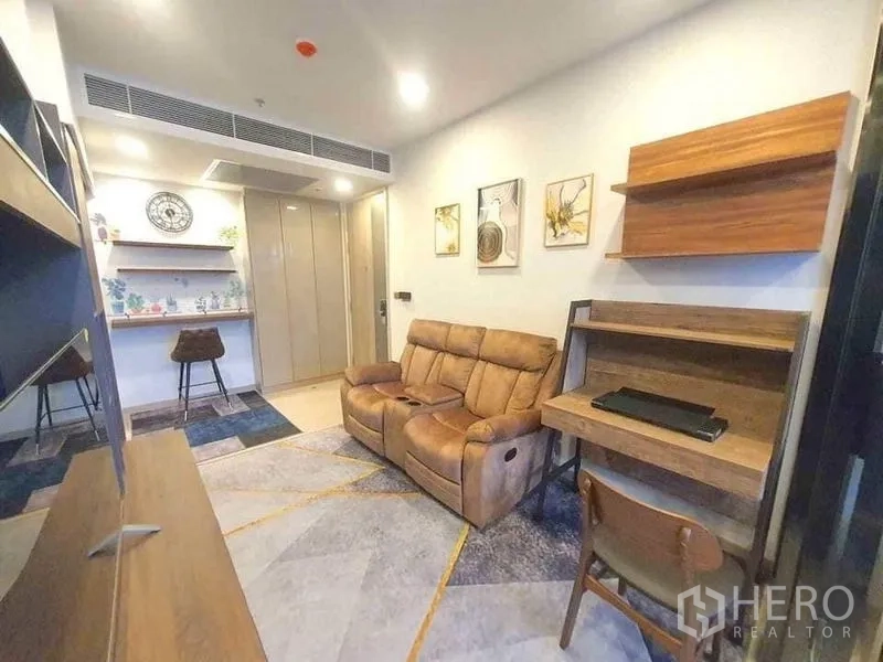 Condominium for rent or sale in Huai Khwang, Bangkok - Living space with sofa, built-in desk, and shelving for storage.