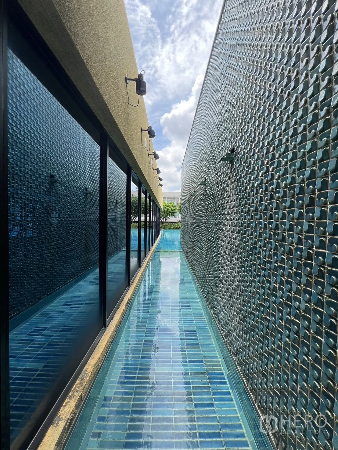 Townhouse for rent in Suan Luang, Bangkok - Modern clubhouse entrance with mural wall and palm trees.