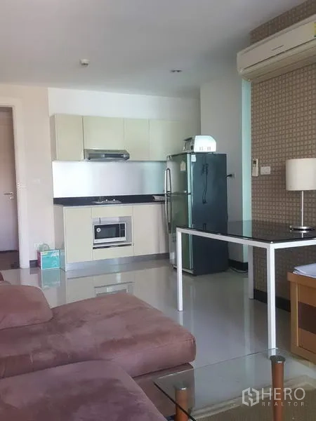 公寓 出租在Khlong Toei, Bangkok - 开放式客厅，棕色沙发、内置小厨房、冰箱与餐桌