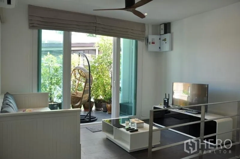 联排别墅 出租或出售在Watthana, Bangkok - 楼上起居室带电视与吊扇，阳台设吊椅与盆栽。