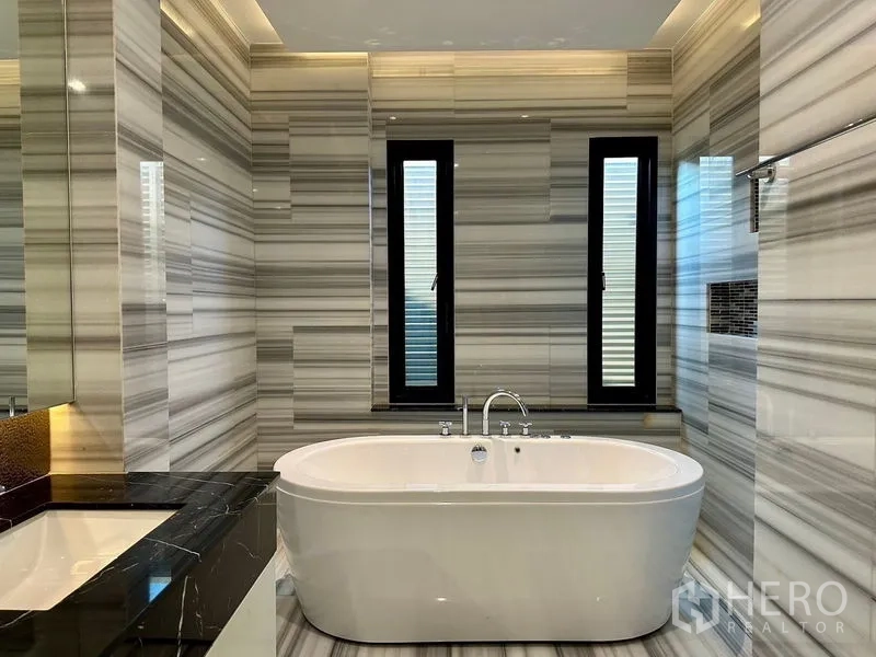 Detached House for rent - Contemporary bathroom featuring a freestanding bathtub, double sinks and vertical windows.