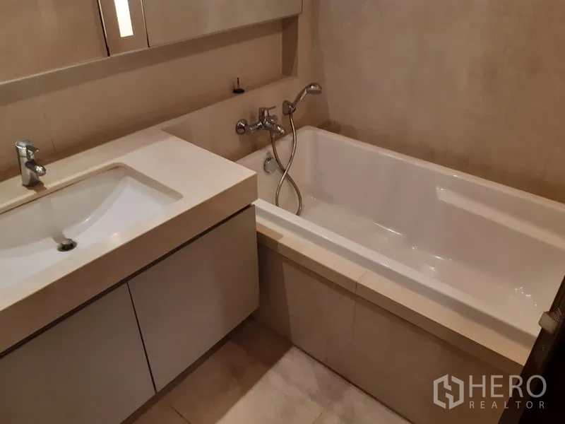 公寓 出租在Watthana, Bangkok - 浴室另一角，嵌入式浴缸配手持花洒，简洁洗手台。