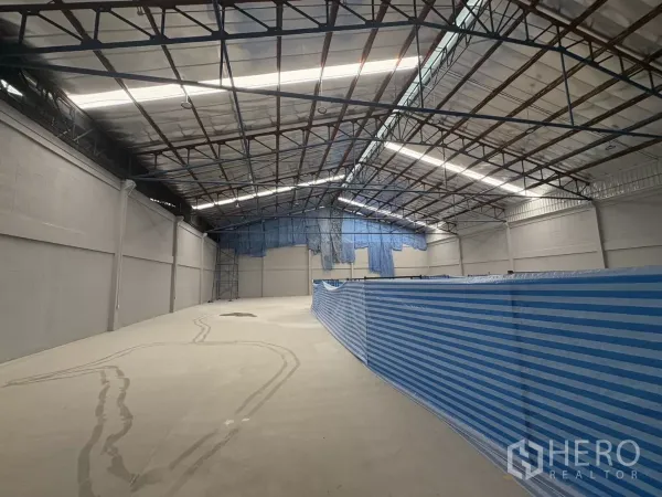 Factory for rent in Bang Phli, Samut Prakan - Spacious warehouse interior with high steel truss roof, skylight panels, and polished concrete floor.