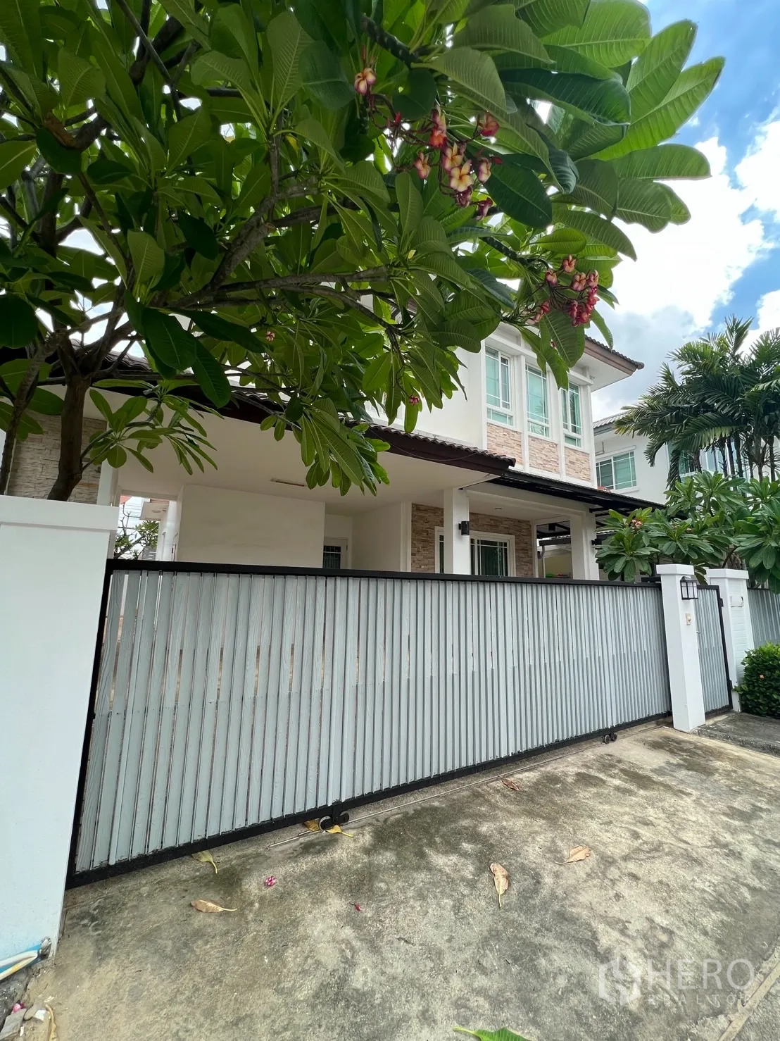Detached House for rent in Bang Kapi, Bangkok - Sliding metal gate and driveway shaded by a frangipani tree at the front of the house.