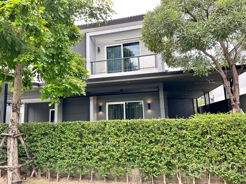 独立式住宅 出售在Prawet, Bangkok - 房屋背面带阳台，落地推拉门、绿篱与成树。