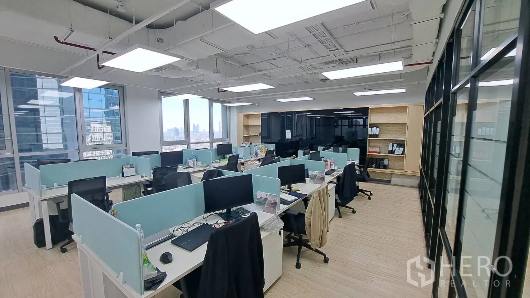 办公空间 出租在Yan Nawa, Bangkok - 临窗工位区，浅蓝隔板与收纳书架