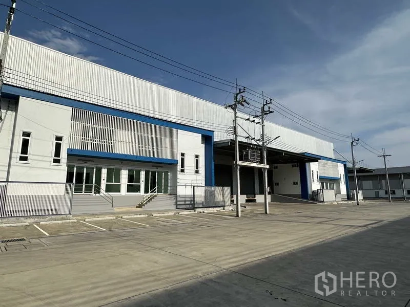 Factory for rent in Bang Sao Thong, Samut Prakan - Modern factory facade in Bang Sao Thong with wide concrete yard, parking, and covered loading bays.