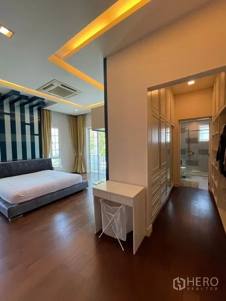 Detached House for rent in Bang Phli, Samut Prakan - Master suite with walk-in closet corridor and bathroom, cove lighting and wood floors.