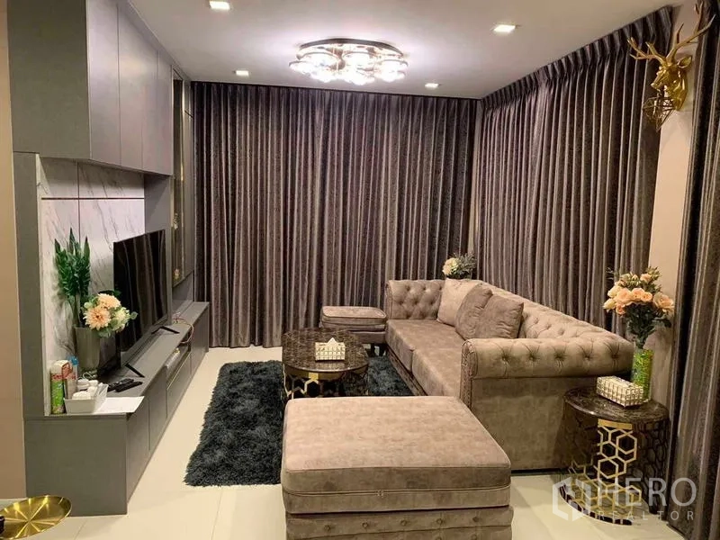 Detached House for sale in Khan Na Yao, Bangkok - Cozy family lounge with tufted sofa, TV media wall, ceiling light and dark drapes.
