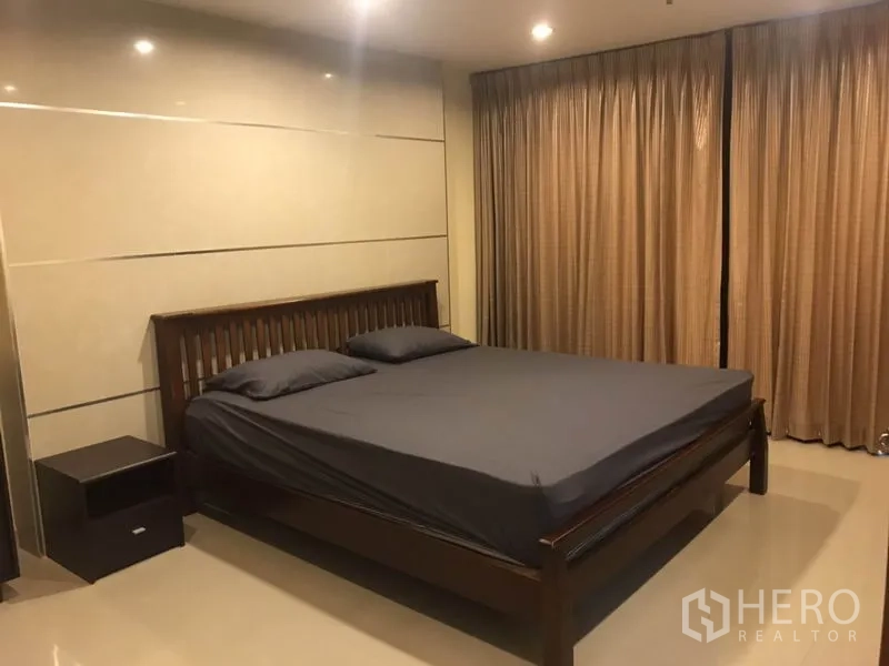 Condominium for rent in Watthana, Bangkok - Primary bedroom with king bed, warm tones and full-length curtains.