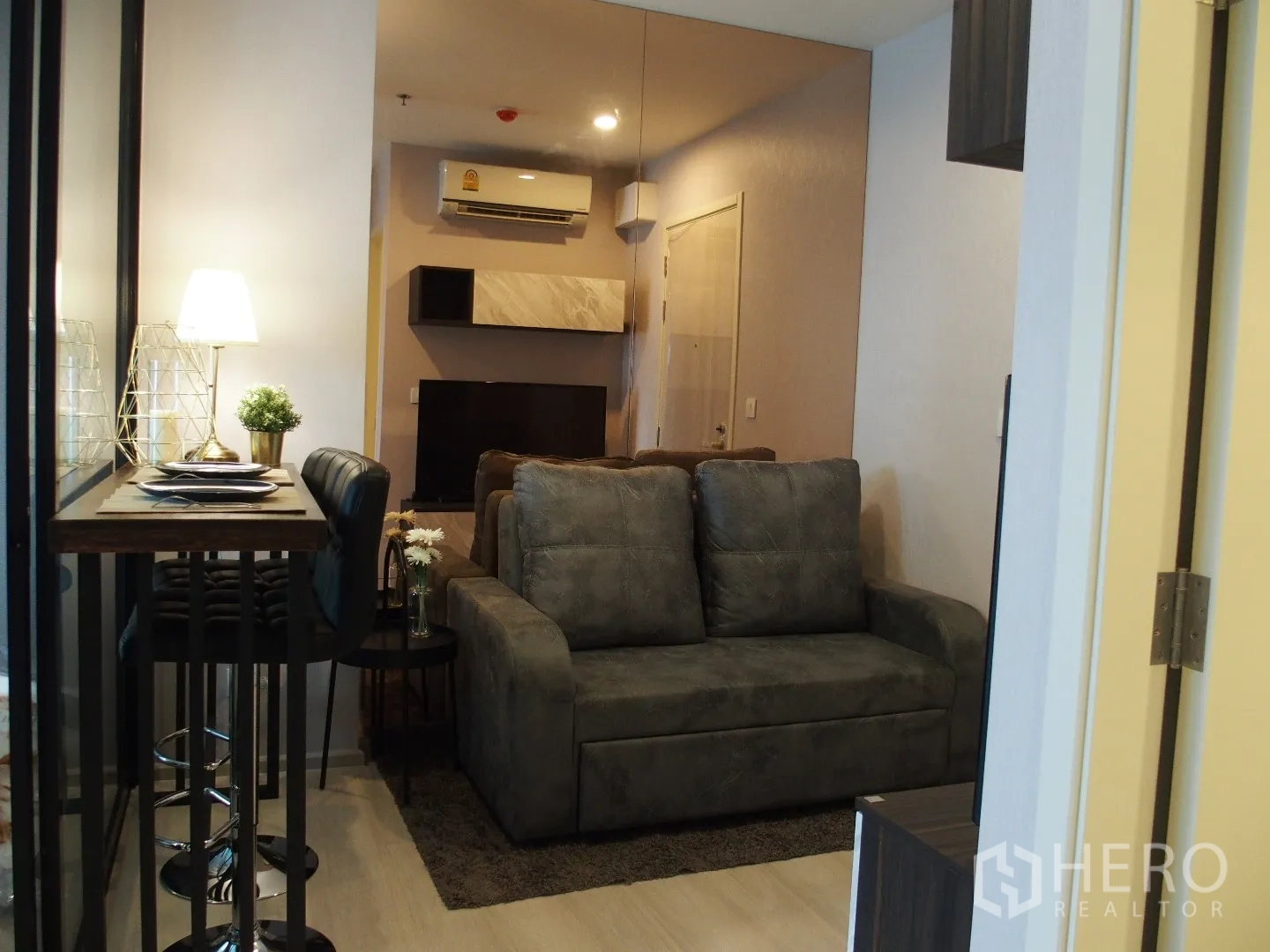 คอนโด ให้เช่าในHuai Khwang, Bangkok - ห้องนั่งเล่นอบอุ่น โซฟาสีเทา ชุดโต๊ะทานอาหารสูง ชั้นวางบิวต์อิน และเครื่องปรับอากาศ