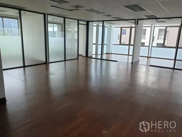 Office Space for rent in Khlong Toei, Bangkok - Spacious office floor with frosted glass partitions, wood floors and grid ceiling lights.