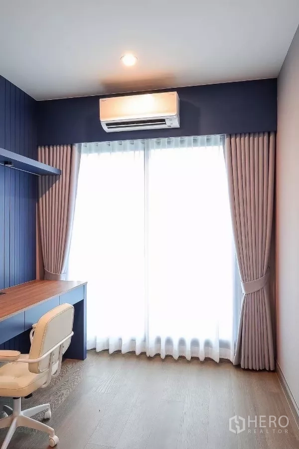 Detached House for rent or sale in Prawet, Bangkok - Compact study with built-in desk and chair, blue accent wall and large curtained glass door.