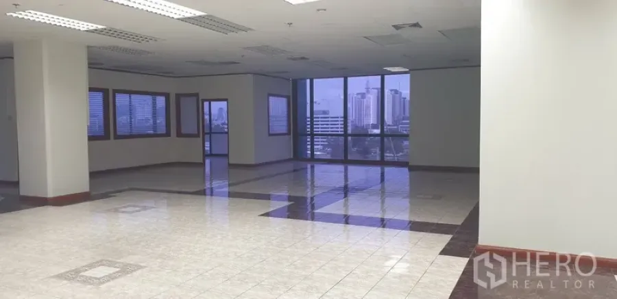 Office Space for rent in Din Daeng, Bangkok - Corner office area with panoramic glazing, skyline outlook, and suspended fluorescent lighting.
