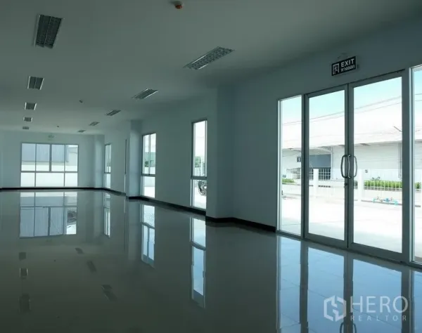Factory for rent in Bang Sao Thong, Samut Prakan - Bright office space with glossy tiled floors, large windows and glass doors facing the compound.