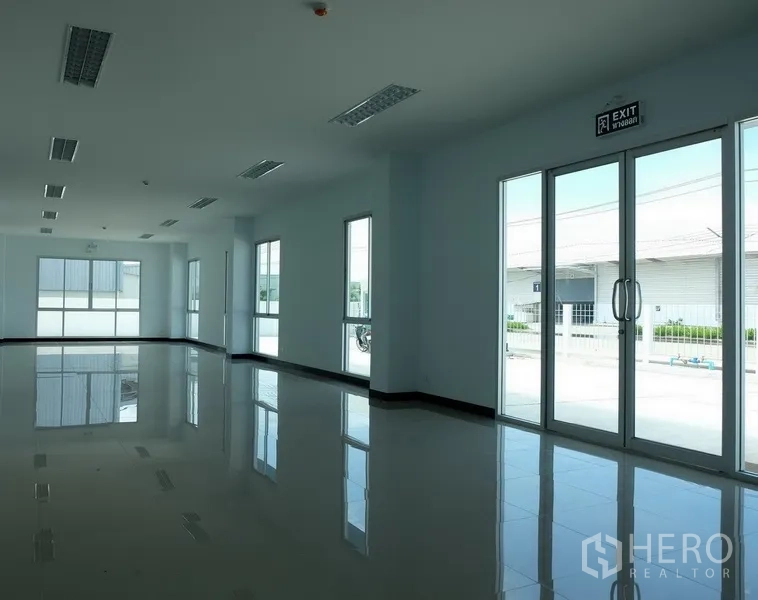 Factory for rent in Bang Sao Thong, Samut Prakan - Bright office space with glossy tiled floors, large windows and glass doors facing the compound.
