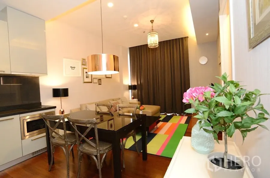 公寓 出租在Watthana, Bangkok - 开放式起居区，现代厨房、吊灯、玻璃餐桌与彩色地毯的通罗公寓