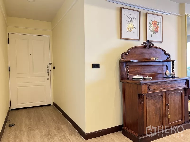 Condominium for rent in Khlong Toei, Bangkok - Entry hallway featuring a solid white door, classic wooden cabinet and light wood flooring.