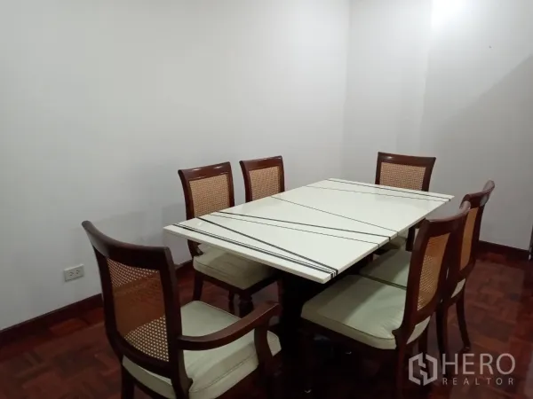 房间 出租在Watthana, Bangkok - 六人餐区，白色餐桌、木椅与简约墙面。