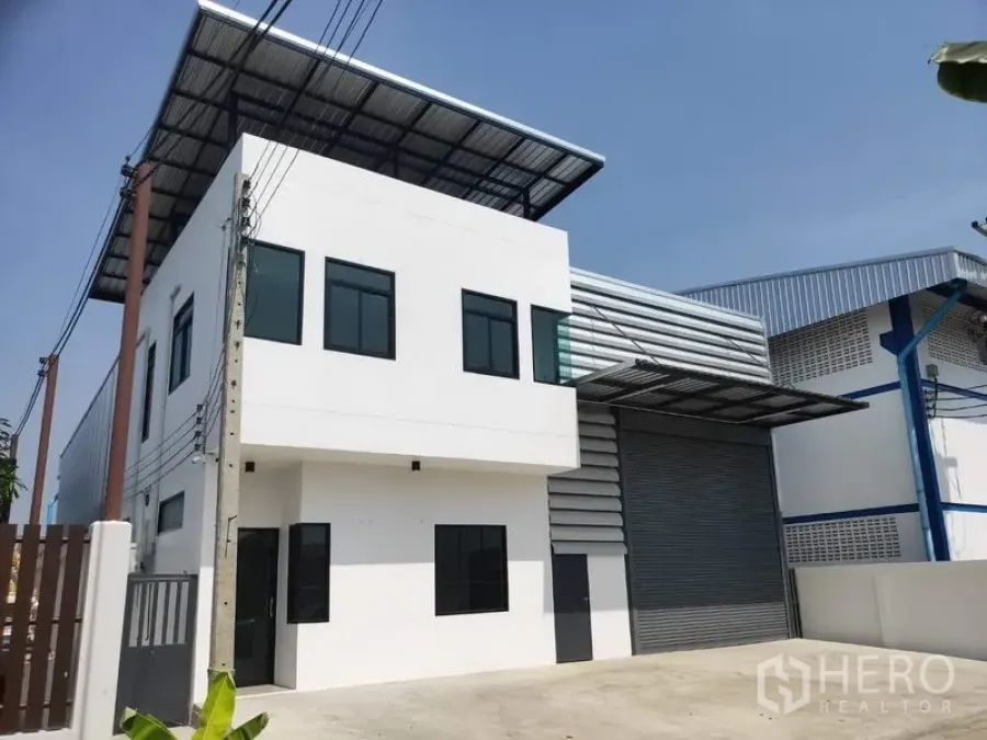 工厂 出租在Lam Luk Ka, Pathum Thani - Lam Luk Ka 现代两层工厂，白色办公室立面与大型卷闸门。