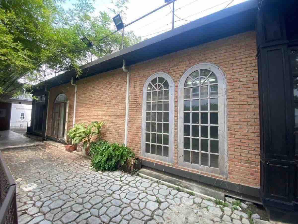 Retail Space for rent in Watthana, Bangkok - Brick facade with arched windows beside a stone-paved walkway and potted plants.