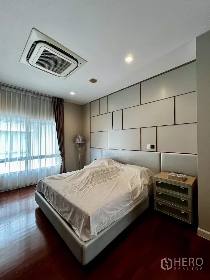 Detached House for rent or sale in Prawet, Bangkok - Spacious bedroom with accent panel wall and sheer-draped window.