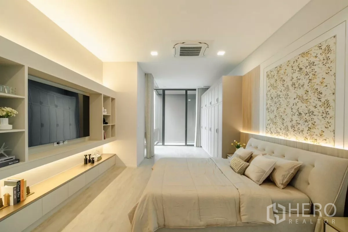 Detached House for rent in Saphan Sung, Bangkok - Spacious bedroom with feature wall art, cassette air‑conditioning, wall‑to‑wall cabinetry, and seating area.