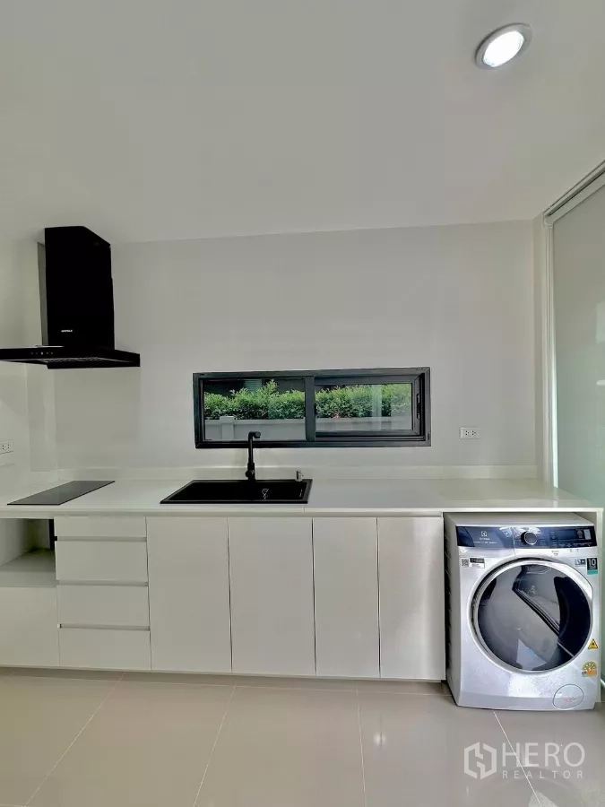 独立式住宅 出租或出售在Prawet, Bangkok - 宽敞备餐区，长台面、黑色水槽与伊莱克斯洗衣机。