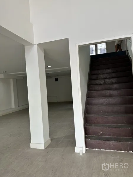 Shophouse for rent in Bang Na, Bangkok - Interior view with sturdy staircase to upper levels and a columned open space.