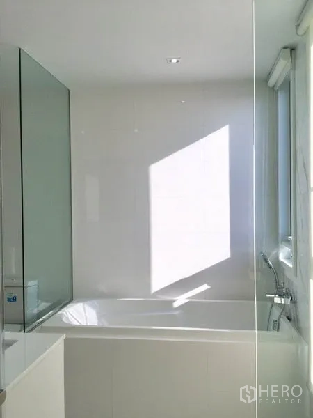 公寓 出租或出售在Watthana, Bangkok - 浴缸紧邻大窗，自然光充沛，配玻璃挡板。