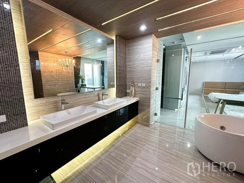 公寓 出租或出售在Khlong Toei, Bangkok - 卫浴间设双台盆、大镜面与通往套房的玻璃门。
