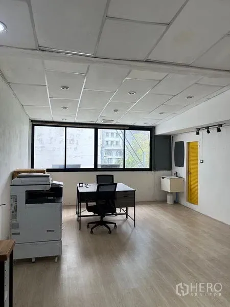 Shophouse for rent in Khlong Toei, Bangkok - Upper-floor workspace with large windows, desk, sink and a yellow door providing natural light.