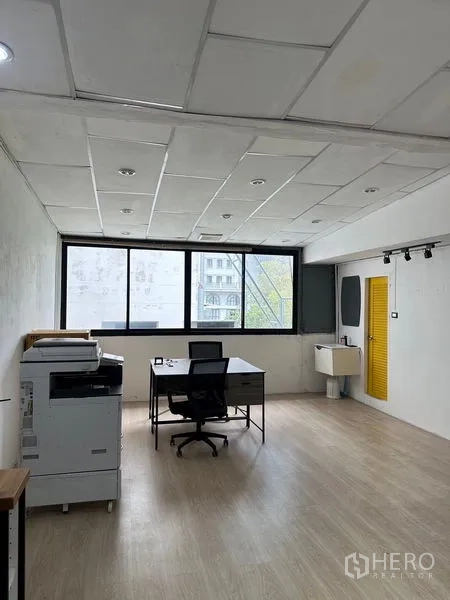 Shophouse for rent in Khlong Toei, Bangkok - Upper-floor workspace with large windows, desk, sink and a yellow door providing natural light.