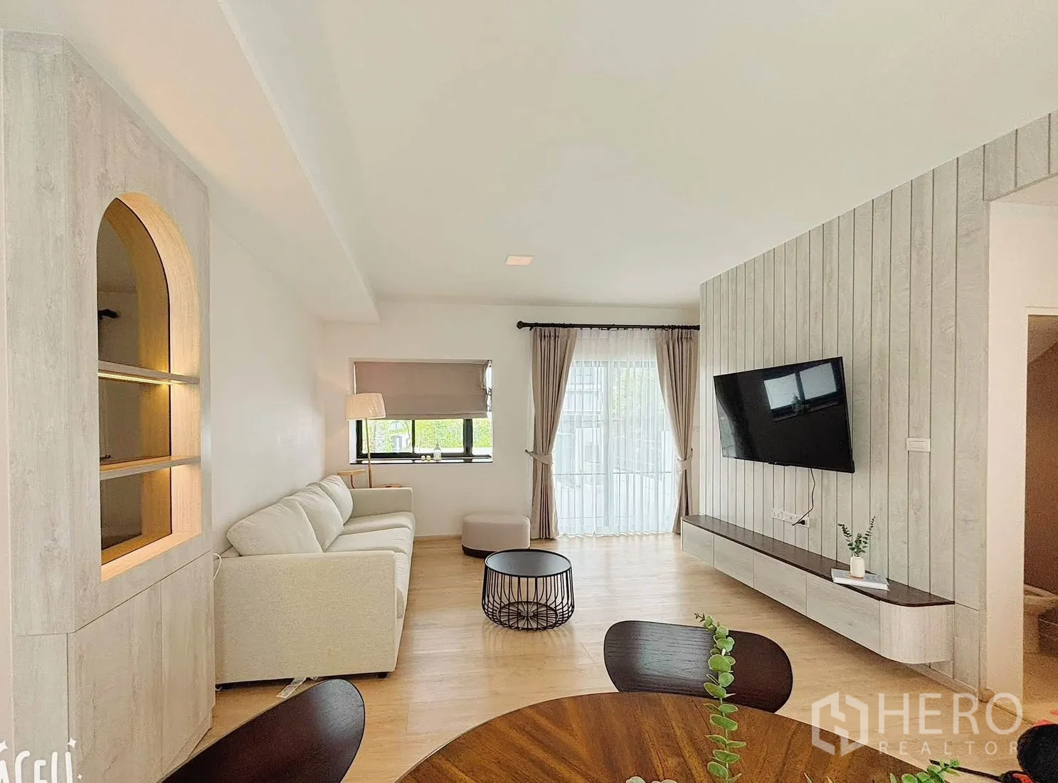 Townhouse for rent in Bang Phli, Samut Prakan - Modern living room with a sofa, wall-mounted TV, and sliding glass doors.