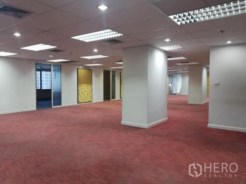 办公空间 出租在Watthana, Bangkok - 宽敞的开放式办公楼层，红色地毯、结构柱和格栅吊顶照明。