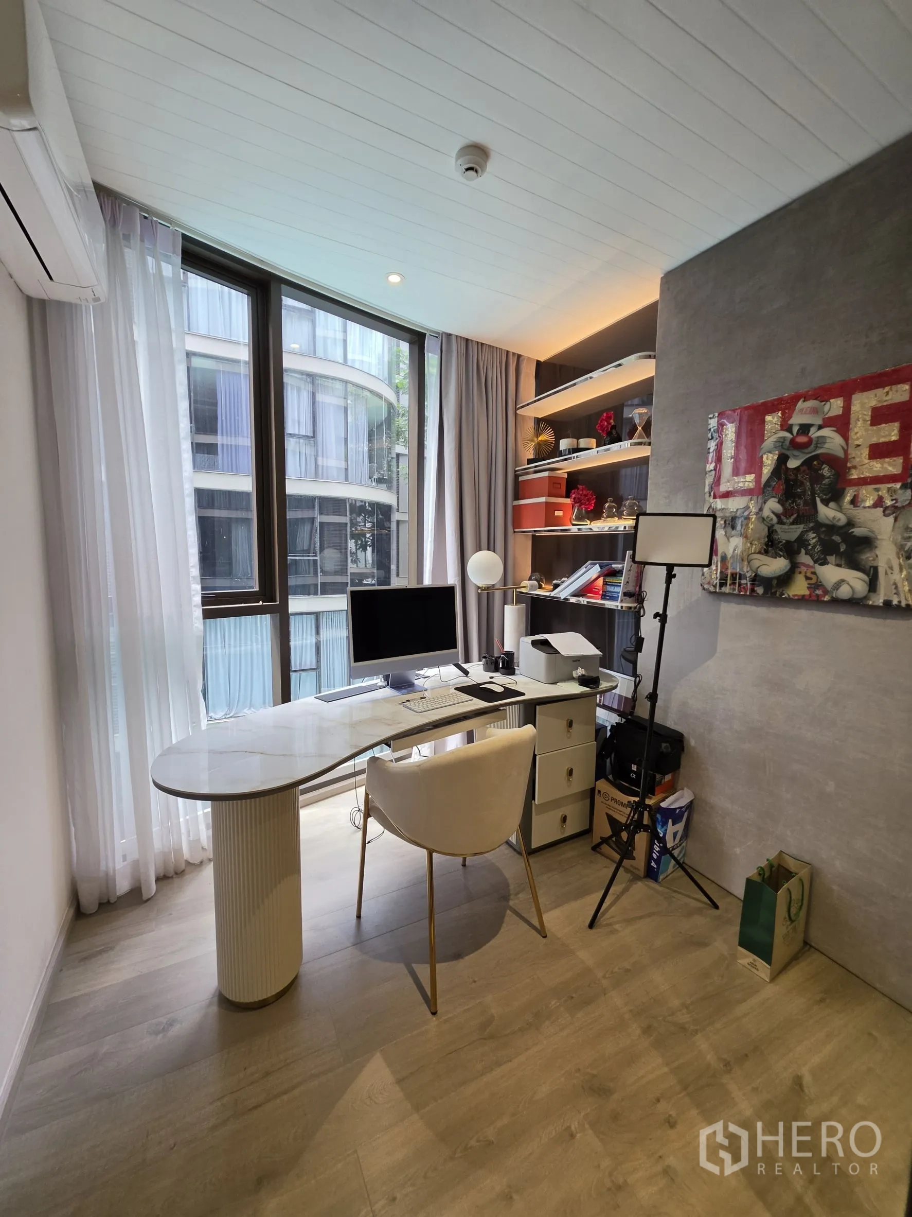 Condominium for rent in Khlong Toei, Bangkok - Spacious home office with curved desk, chair, and wide windows.