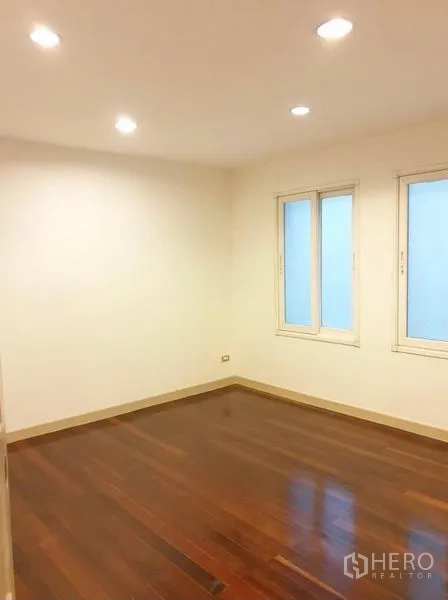 Townhouse for rent or sale in Chatuchak, Bangkok - Bedroom with wooden flooring, recessed ceiling lights and twin windows.