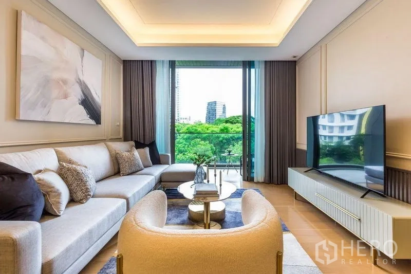 Condominium for rent in Pathum Wan, Bangkok - Living room facing the balcony with expansive treetop view and a large TV.