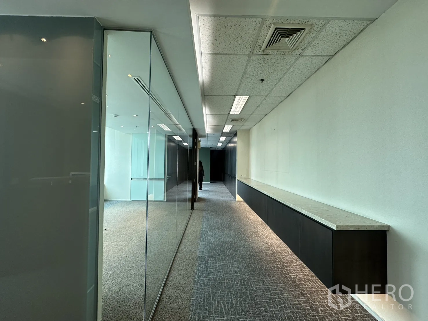 Office Space for rent in Watthana, Bangkok - Carpeted corridor with glass partitions and long built-in cabinet underlighting.